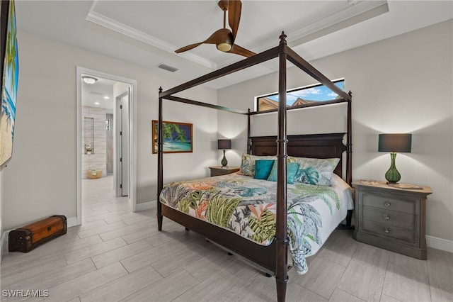 bedroom featuring connected bathroom, a tray ceiling, ceiling fan, and crown molding