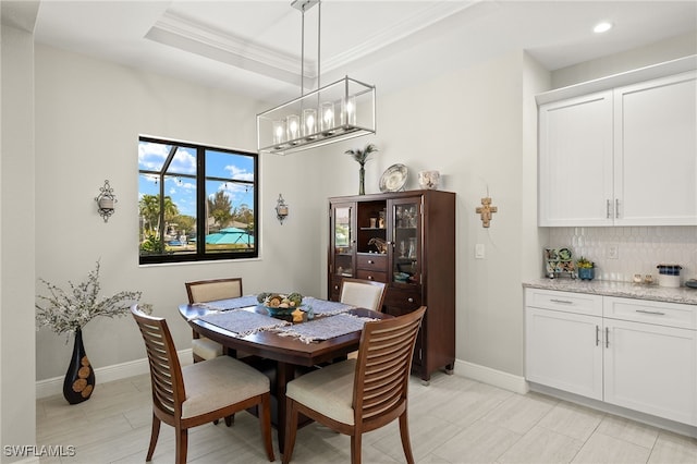 dining area with a tray ceiling and crown molding