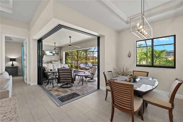 dining area featuring ceiling fan with notable chandelier, a raised ceiling, and plenty of natural light