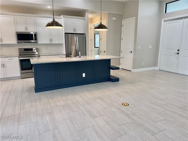 kitchen with stainless steel appliances, tasteful backsplash, an island with sink, pendant lighting, and white cabinets