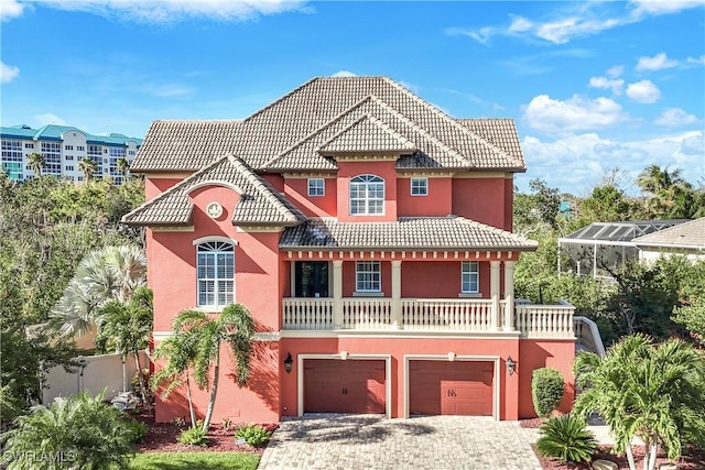 mediterranean / spanish home with a garage, decorative driveway, a tile roof, and stucco siding