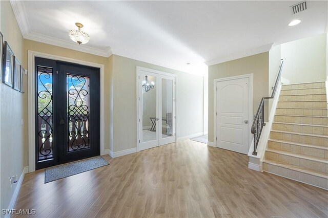 entryway featuring french doors, crown molding, and hardwood / wood-style floors