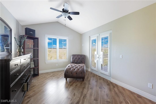 living area with french doors, a ceiling fan, vaulted ceiling, wood finished floors, and baseboards