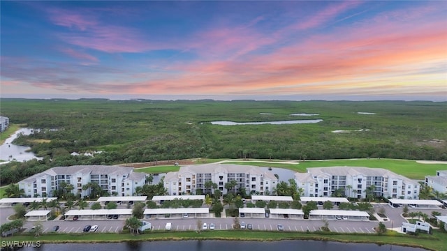 aerial view at dusk featuring a water view