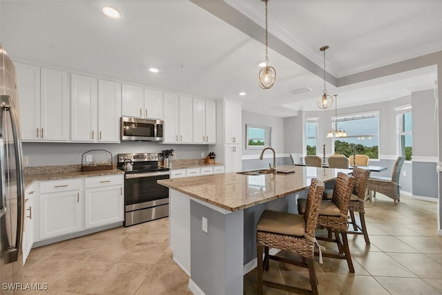 kitchen featuring appliances with stainless steel finishes, decorative light fixtures, a wealth of natural light, sink, and an island with sink