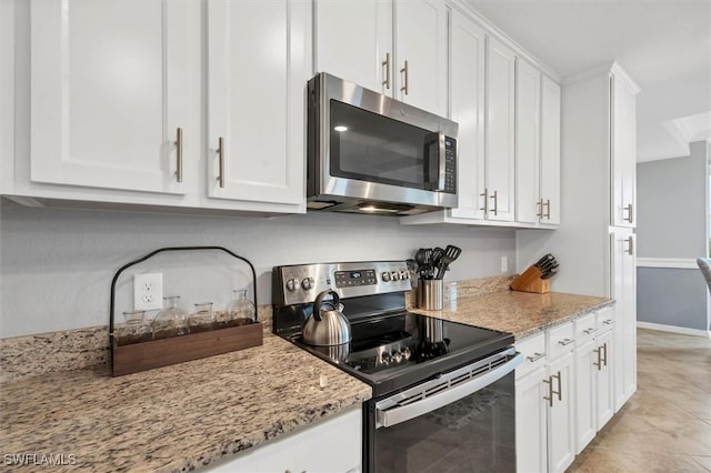 kitchen featuring white cabinetry, light stone countertops, light tile patterned floors, and stainless steel appliances