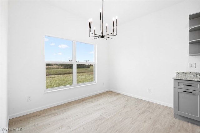 unfurnished dining area featuring light hardwood / wood-style flooring and an inviting chandelier