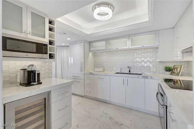 kitchen with stainless steel appliances, a raised ceiling, sink, white cabinetry, and wine cooler