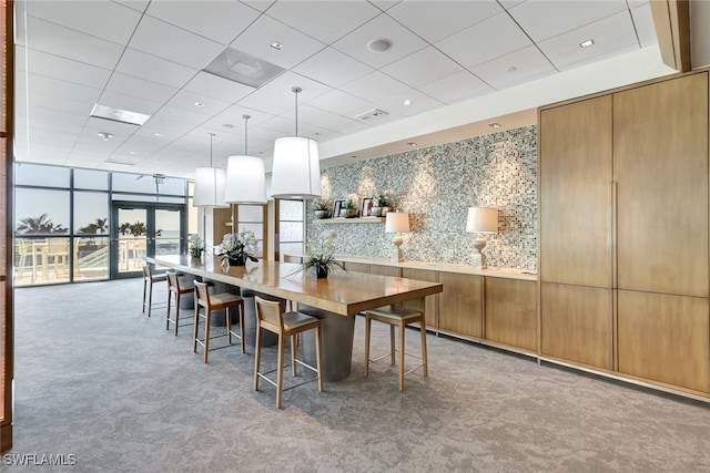 carpeted dining room featuring a drop ceiling, expansive windows, and french doors