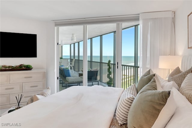 bedroom featuring access to exterior, a water view, and a wall of windows