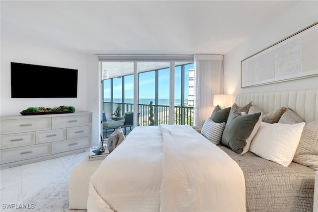 bedroom featuring access to outside, a wall of windows, and a water view