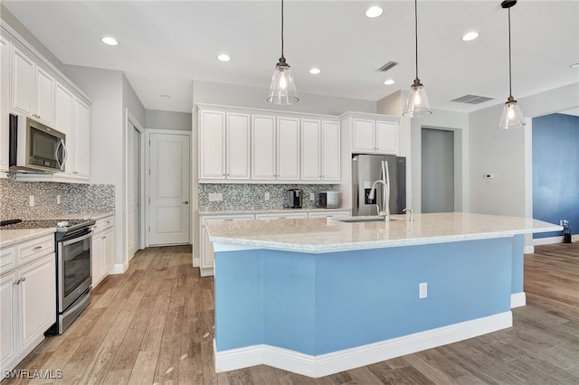 kitchen with appliances with stainless steel finishes, white cabinets, and an island with sink