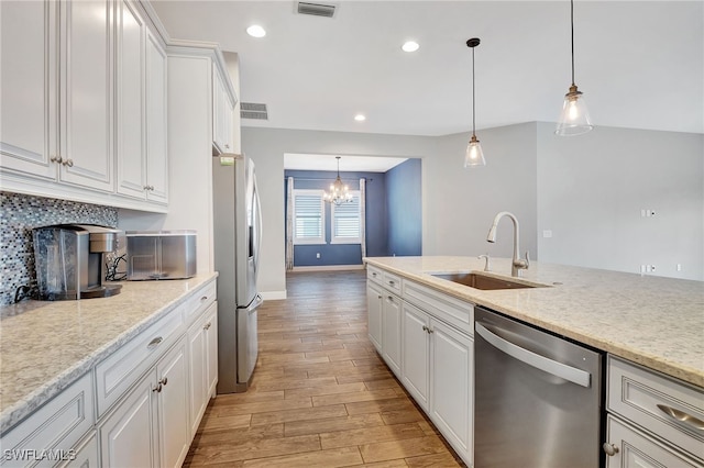 kitchen with stainless steel appliances, sink, pendant lighting, white cabinetry, and light hardwood / wood-style floors