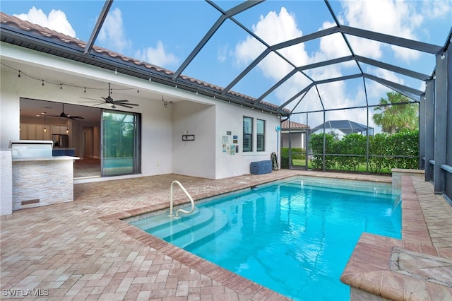 view of swimming pool featuring a patio area, glass enclosure, and ceiling fan