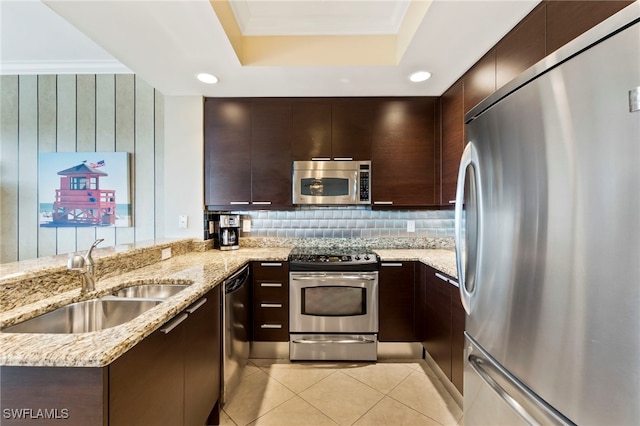 kitchen featuring sink, backsplash, light stone counters, stainless steel appliances, and dark brown cabinets