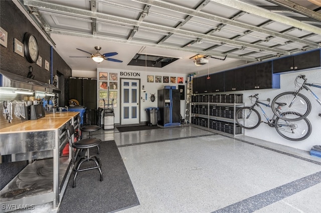 garage with black refrigerator with ice dispenser, ceiling fan, and a garage door opener