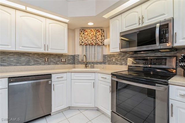 kitchen featuring stainless steel appliances, sink, tasteful backsplash, white cabinets, and light tile patterned flooring