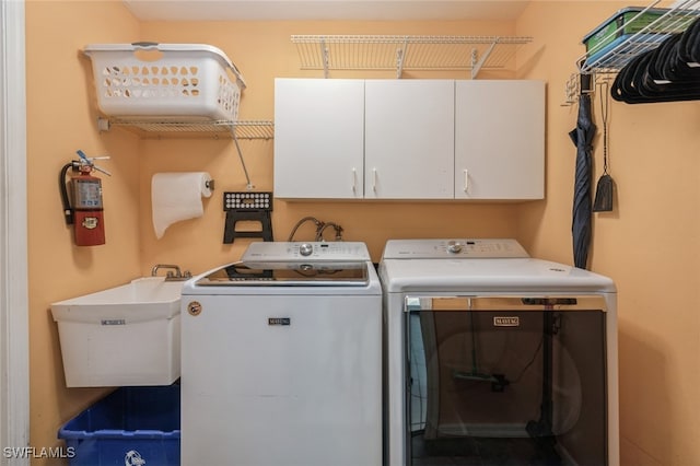 clothes washing area with sink, cabinets, and washing machine and clothes dryer