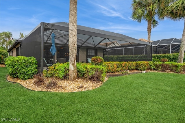 rear view of property featuring a lawn and a lanai