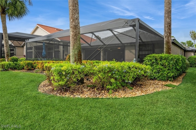 back of property featuring a lawn and glass enclosure