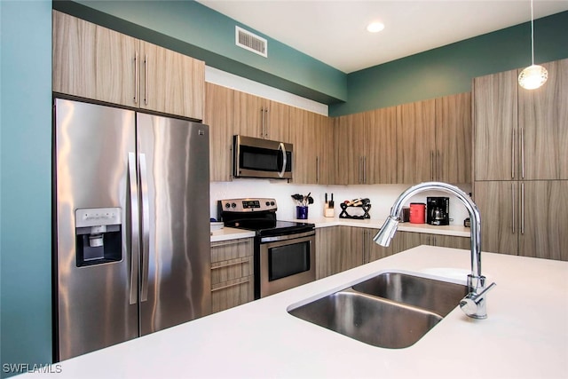 kitchen featuring stainless steel appliances, sink, and pendant lighting