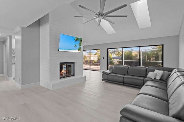 living room with ceiling fan, a fireplace, high vaulted ceiling, and light hardwood / wood-style flooring