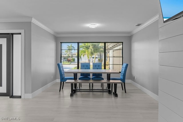 dining space featuring ornamental molding and light hardwood / wood-style flooring