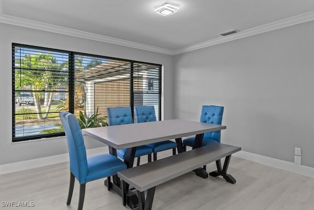 dining room featuring light wood-type flooring, ornamental molding, and a wealth of natural light