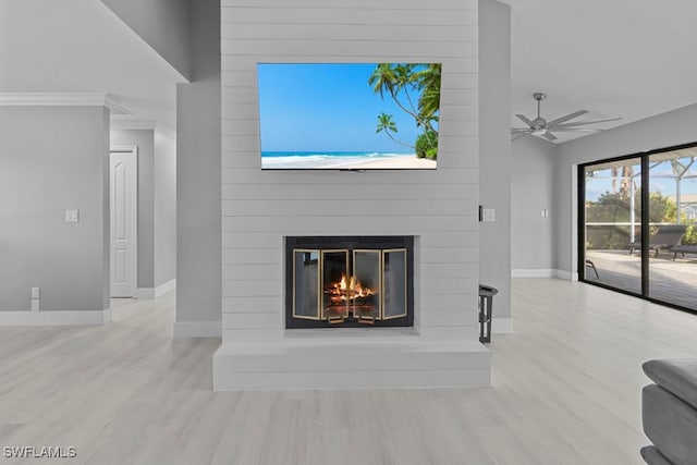 living room with a large fireplace, light hardwood / wood-style flooring, ceiling fan, and ornamental molding