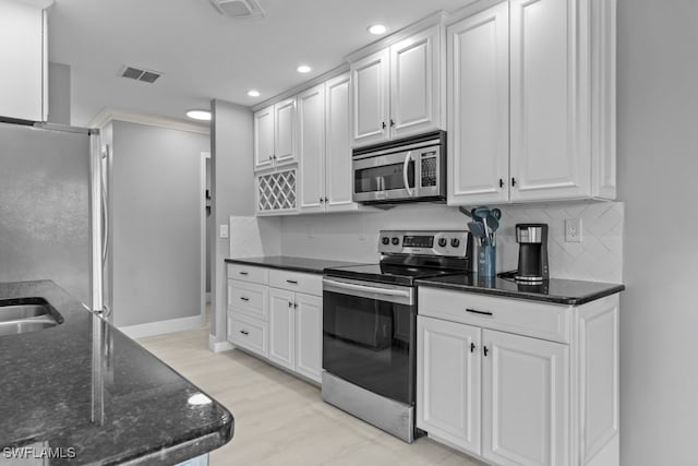 kitchen featuring white cabinets, stainless steel appliances, light hardwood / wood-style flooring, and dark stone countertops