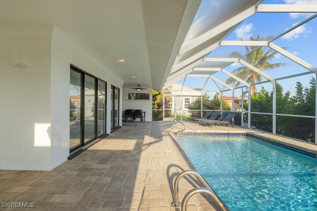 view of pool featuring glass enclosure, ceiling fan, and a patio area