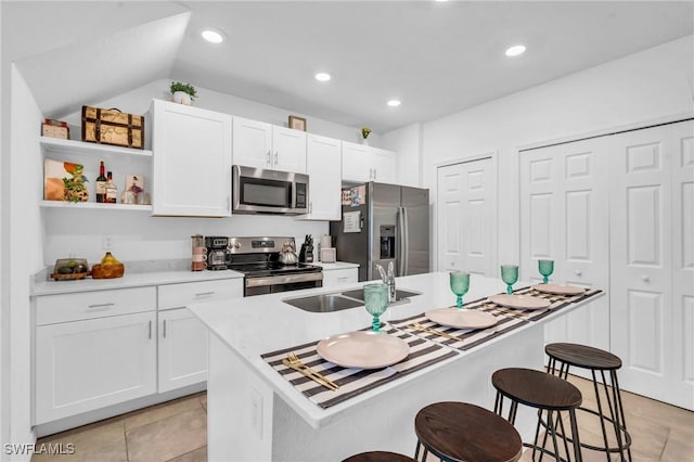 kitchen with a breakfast bar, sink, stainless steel appliances, and an island with sink