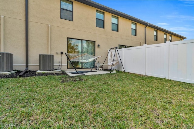 back of property featuring central AC, a patio area, and a lawn