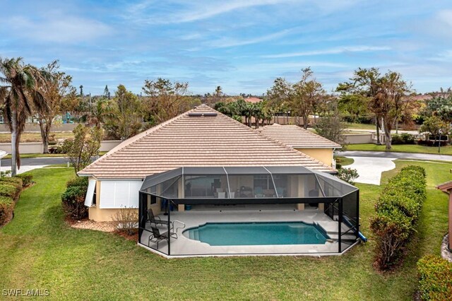 back of house with a lanai, a patio area, and a lawn