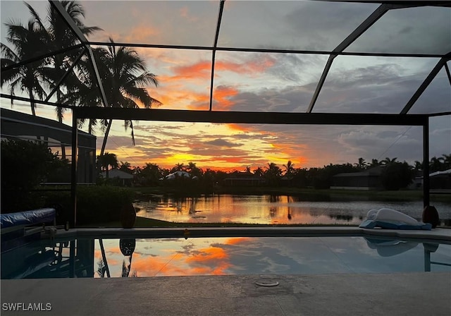 pool at dusk featuring a lanai and a water view