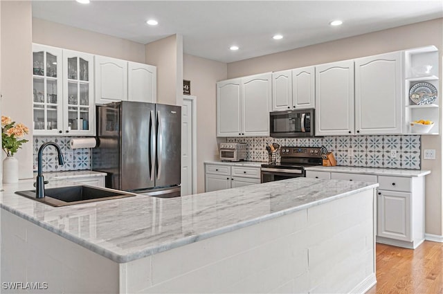 kitchen featuring stainless steel appliances, light stone countertops, sink, and white cabinets