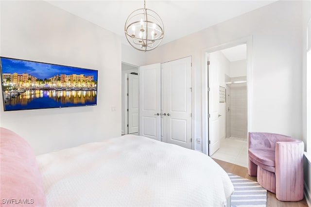 bedroom with an inviting chandelier, ensuite bath, and light wood-type flooring