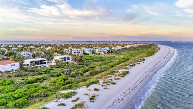 aerial view at dusk with a view of the beach and a water view