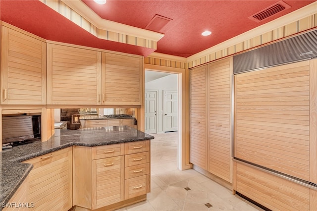 kitchen featuring light brown cabinets, kitchen peninsula, and a textured ceiling