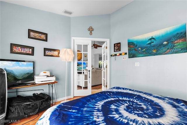 bedroom with french doors and hardwood / wood-style flooring