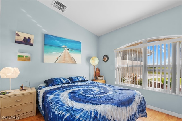 bedroom with light wood-type flooring and vaulted ceiling