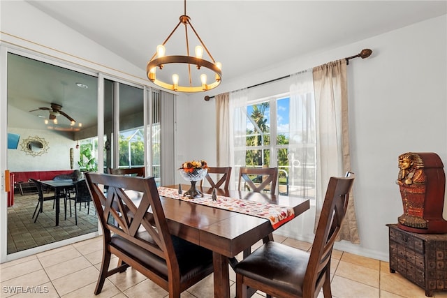 dining area with light tile patterned floors, ceiling fan with notable chandelier, and vaulted ceiling