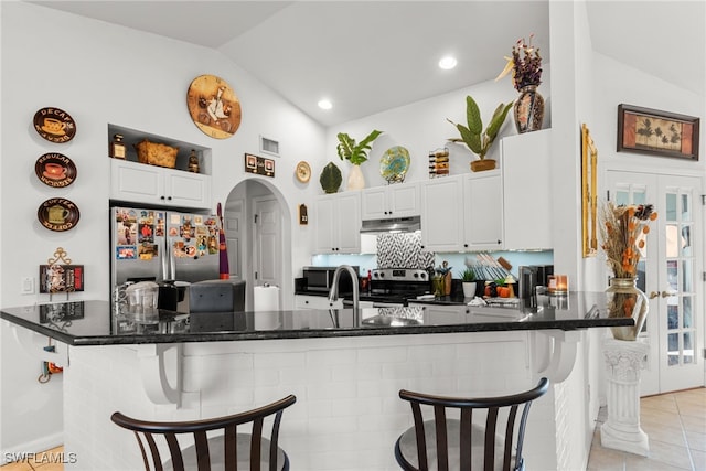 kitchen with kitchen peninsula, appliances with stainless steel finishes, white cabinets, and vaulted ceiling