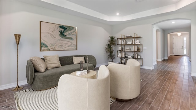 living room featuring a raised ceiling and wood-type flooring