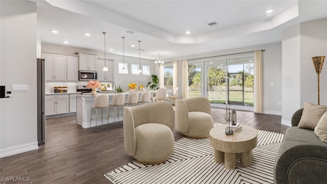 living room featuring a raised ceiling and dark wood-type flooring