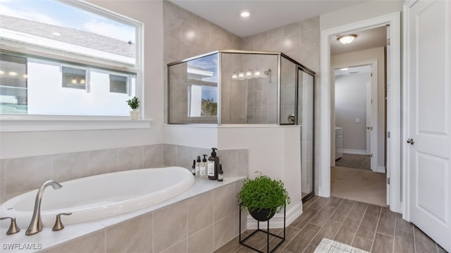 bathroom with wood-type flooring and shower with separate bathtub