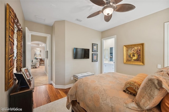 bedroom with connected bathroom, ceiling fan, and light hardwood / wood-style floors