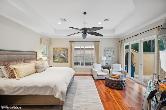 bedroom featuring french doors, access to outside, a tray ceiling, ceiling fan, and wood-type flooring