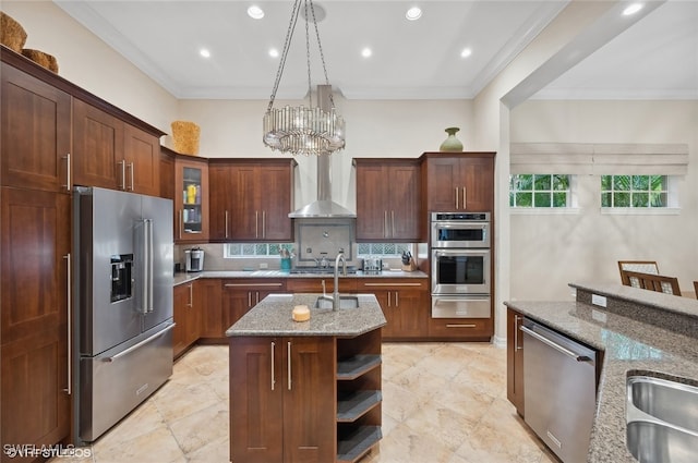 kitchen with crown molding, light stone countertops, a center island with sink, and stainless steel appliances