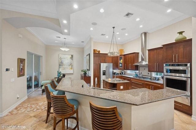 4908 Rustic Oaks Cir, Naples, FL 34105 - kitchen featuring a large island, wall chimney range hood, stainless steel appliances, a sink, and crown molding